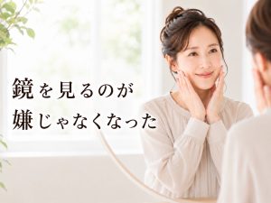 明るい洗面スペースで鏡を見ながら頬に手を添えて微笑む女性。シミ・乾燥・くすみなどの肌悩みを責めず、自分の肌を大切に育てることを伝える新宿区Sunflowerの美容コラム